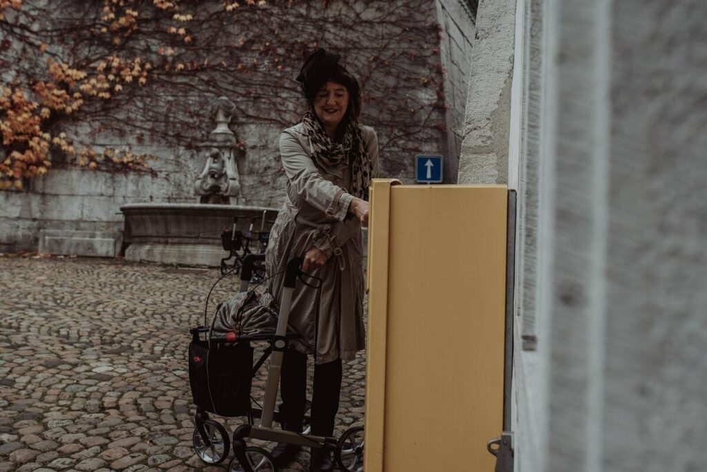 Person mit Rollator welche Post einwirft am Briefkasten der Schweizer Post